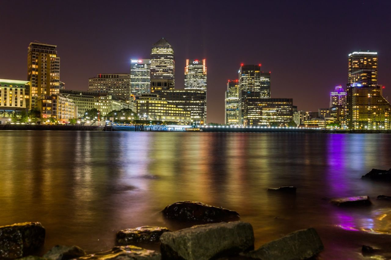 Stunning evening view of London's Canary Wharf skyline reflecting on the Thames.